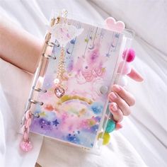 a person is holding a small notebook with unicorns on it and stars in the sky