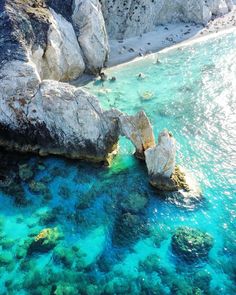 the water is crystal blue and clear with rocks on either side that are surrounded by green algae