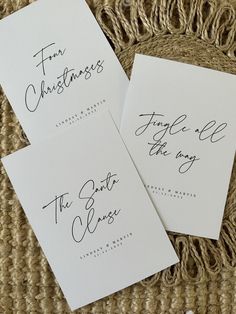 three white cards with calligraphy on them sitting on a wicker tablecloth area