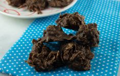 chocolate cookies are on a blue napkin next to a white plate with polka dot paper