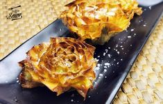 two pieces of artichoke sitting on top of a black plate next to each other