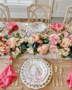 the table is set with pink flowers and gold cutlery, along with silverware