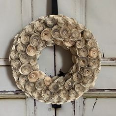 a wreath made out of rolled up paper is hanging on a door with a black ribbon