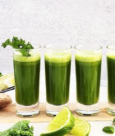 four glasses filled with green juice and garnishes