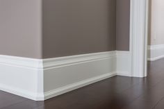 an empty room with hard wood floors and white trim