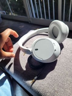 a pair of white headphones sitting on top of a table next to a window