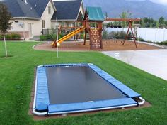 an inflatable trampoline is on the grass near a playground and house