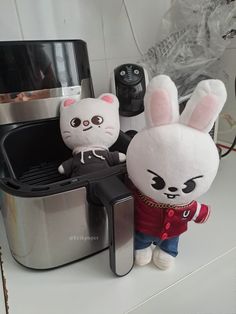 two stuffed animals sitting on top of a toaster