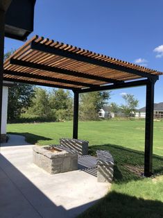 an outdoor patio area with benches and fire pit in the middle of it on a sunny day