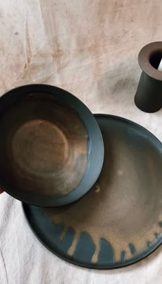 two black plates sitting next to each other on top of a white cloth covered table