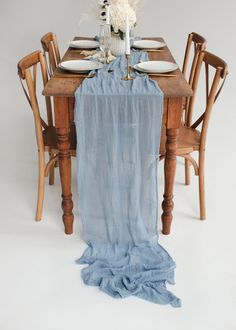 the table is set with blue linens and white flowers in vases on it