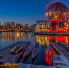 the city skyline is lit up at night as boats are docked in the water and on the dock