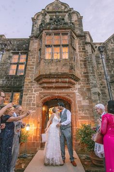 a bride and groom standing in front of an old building with confetti thrown on them