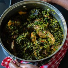 a person holding a pot filled with food on top of a table