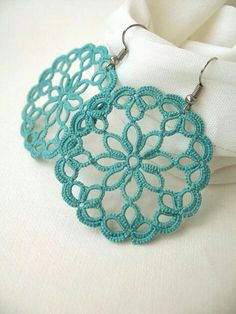 two pairs of blue crochet earrings sitting on top of a white cloth covered table