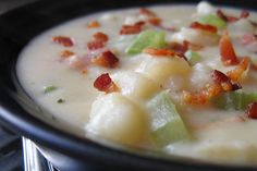 a close up of a bowl of soup on a table with utensils in the background