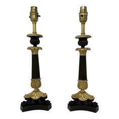 a pair of black and gold candlesticks sitting next to each other on stands