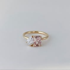 two stone engagement ring in yellow gold with white diamonds on each side, set against a plain background