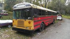 a red and yellow school bus parked on the side of a road next to other cars