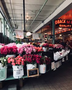 flowers are on display in buckets at an outdoor market