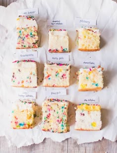 nine pieces of cake with different colored sprinkles on them sitting on a piece of parchment paper