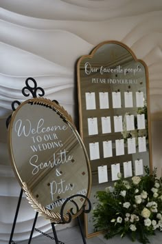 there is a mirror with writing on it next to a flower arrangement and a sign