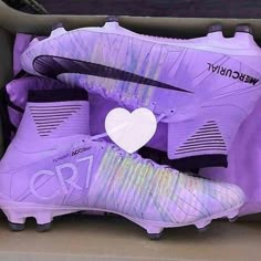 a pair of purple nike soccer cleats in a shoe box with a heart on it