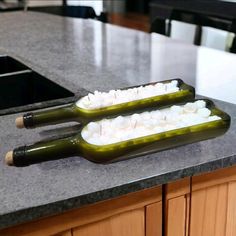 two bottles filled with food sitting on top of a counter next to a sink in a kitchen