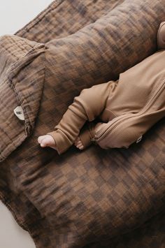 a baby laying on top of a brown pillow