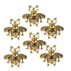 six gold bee brooches on white background