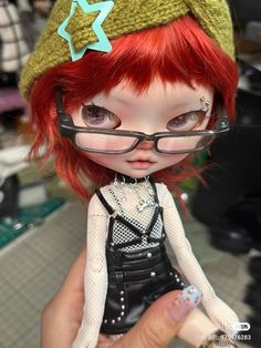 a doll with red hair wearing glasses and a hat