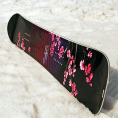 a snowboard with pink flowers on it laying in the snow