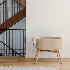 a white chair sitting in front of a stair case next to a wooden handrail