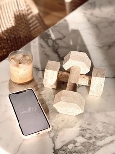 a cell phone sitting on top of a marble table next to some cubes and candles