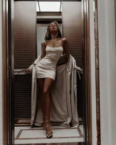 a woman in a short dress sitting on an elevator