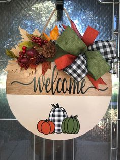 a welcome sign hanging from the side of a glass door with pumpkins and gourds on it