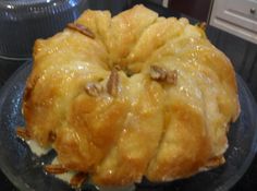 a pastry with pecans on top is sitting on a glass plate, ready to be eaten