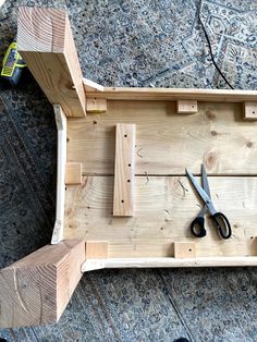 a pair of scissors sitting on top of a piece of wood next to plywood