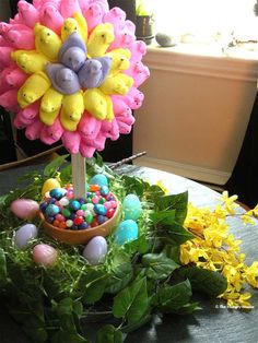 an arrangement of fake flowers and candies on a table