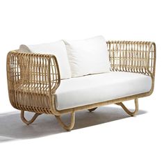 a wicker couch with white pillows on it