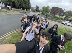 a group of young people dressed in school uniforms posing for a photo on the street