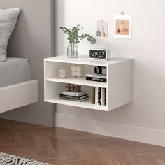 a white book shelf with books on top of it next to a neatly made bed