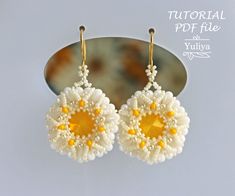 a pair of white and yellow beaded flower earrings on a hook - back mirror