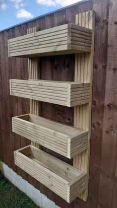 three wooden shelves sitting next to each other on the side of a fenced in area