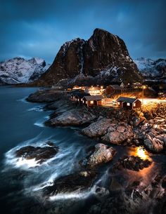 an island with some houses on top of it and mountains in the background at night