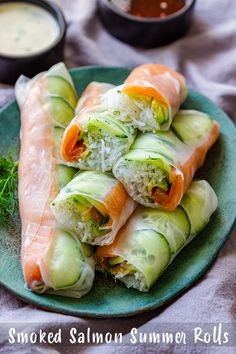 a plate filled with rolls covered in cucumber and carrots next to dipping sauce