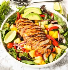 a white bowl filled with chicken, avocado, and mixed veggies