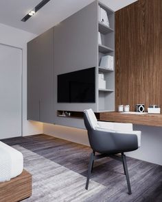 a room with a chair, desk and television on the wall