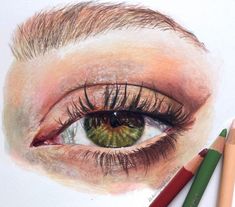 a drawing of an eye with colored pencils next to it