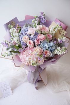 a bouquet of flowers sitting on top of a white table next to a card board